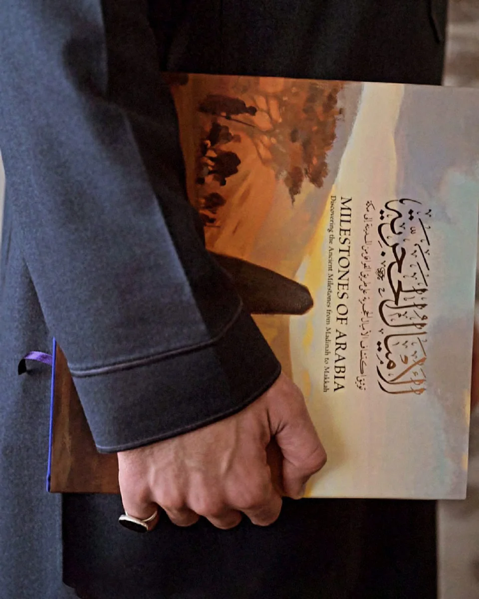 A hand holding a copy of Milestones of Arabia