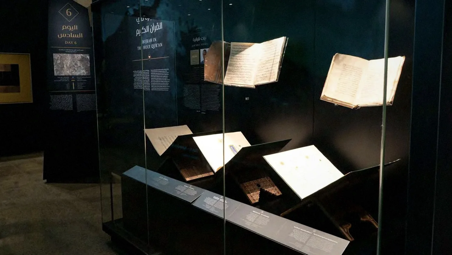 Manuscripts open in glass cases in a darkened exhibition gallery