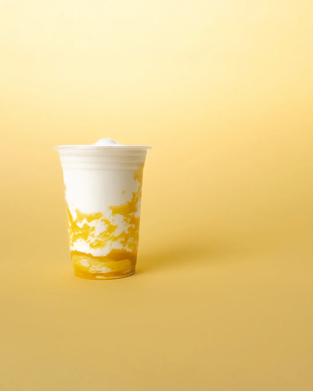 A MYLK mango and cream drink on a yellow ground