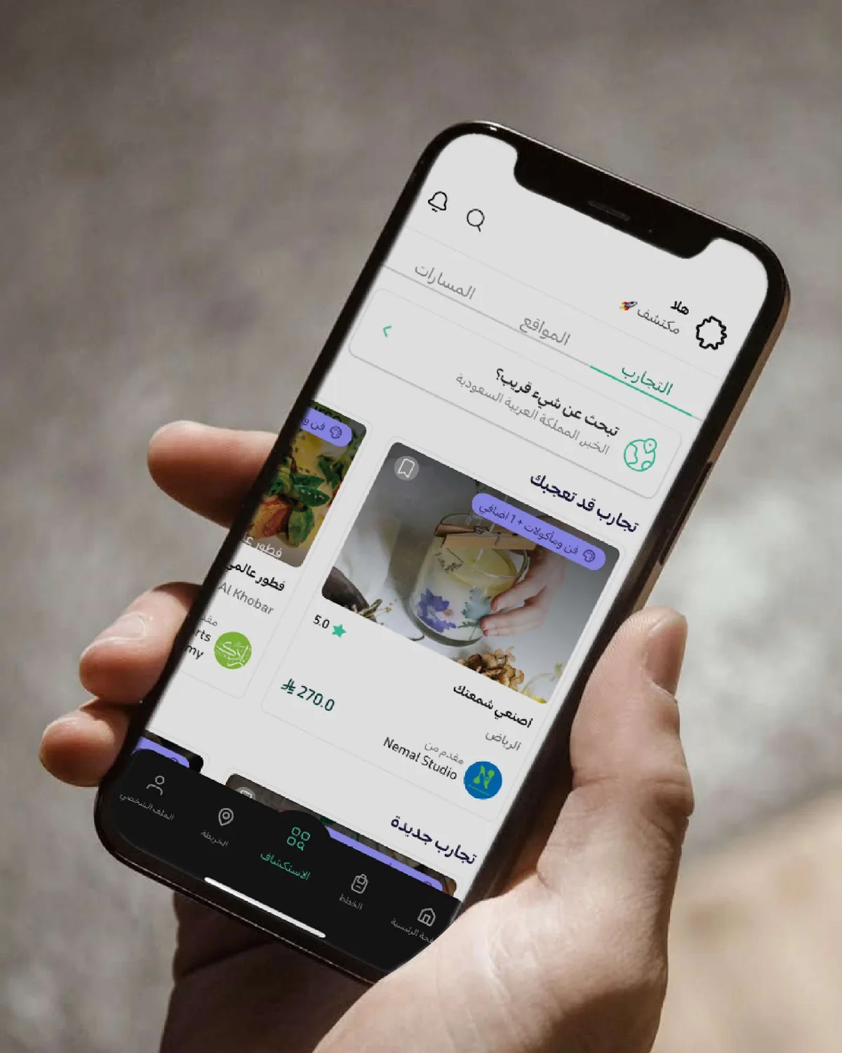 A hand holding a phone that shows the Hislo application in Arabic