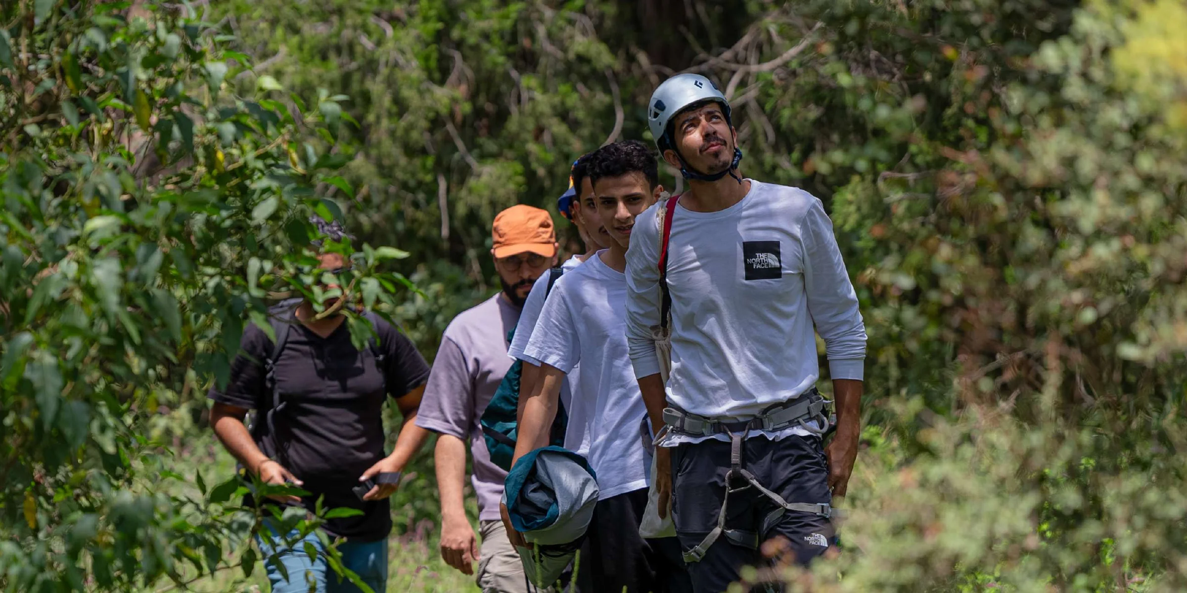 A group of walkers in helmets on a green trail